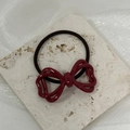 Detalle de un coletero con lazo burdeos sobre fondo de piedra blanca para coletas - Rojo