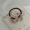 Detail von marmoriertem Schleifen-Haargummi mit elastischem Band auf beigem Travertin - Rosa