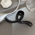 Dettaglio di una molletta per capelli francese nera lucida con denti fini su sfondo artistico - Nero