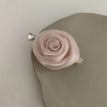 Detail einer rosa Stoffrose-Haarklammer mit glänzendem Herzkristall auf Steintablett - Rosa