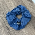 Blauer Denim-Haargummi mit weißen Punkten und Webetikett auf Holzhintergrund - Haargummi / Dunkelblaues Haargummi