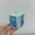 Détail des élastiques à cheveux bleus sur un support en carton avec texte - Série Bleue