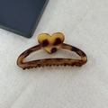 Detail of tortoise shell claw clip with heart motif on textured beige fabric background - Matte Hollow Half-round Style