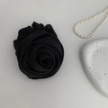 Detail of elegant black silk rose hair accessory with decorative pearls on a white plate - Black
