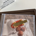 Dettaglio di una catena di lana colorata intrecciata su un fermaglio in metallo dorato - Marrone