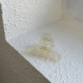 Detailed macro view of the cream pearl acetate hair claw clip with golden handmade logo - Aurora Iridescent