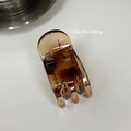 Close-up of small amber tortoiseshell hair claw clip with smooth resin finish on white surface - Amber