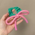 Vue détaillée du grand nœud en tissu rose et du chouchou élastique vert - Chouchou Vert Avec Nœud Rose / Chouchou Vert