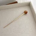 Detailed view of minimalist gold hair pin with a brown spherical bead on beige fabric - Light Tortoiseshell