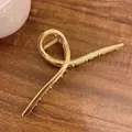 Detail of 13.5cm large golden metal hair claw clip with a twisted minimalist design - Gold