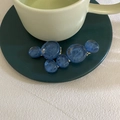 Details von zwei blauen Kristall-Haarklammern an einem grünen Keramiktassenrand - Dunkelblau