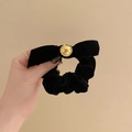 Close-up of black velvet bow scrunchie featuring a decorative gold metal buckle accent - Hair Tie