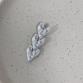 Detail van de zilveren hartvormige haarspeld met een gehamerde metalen textuur en glans - Zilver