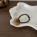 Detail eines braunen elastischen Haargummis mit bernsteinfarbenem Harzknopf und Gravur - Braun