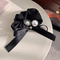 Detail van zwarte satijnen scrunchie met witte parels, lintstrik en kleine metalen hanger - Zwart