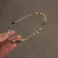 Dettaglio di un cerchietto in metallo con cristalli grigi e trasparenti scintillanti - Grigio
