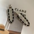 Detail showing two silver metal chain hair clips with black weave on a magazine - Silver Woven Leather Style