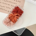 Detail of multi-colored high-elastic hair ties stored in a clear rectangular plastic case - Orange