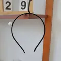 Dettaglio di un cerchietto nero minimalista con una grande perla bianca decorativa su base sottile - Perla Singola