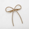 Dettaglio fermaglio per capelli a fiocco dorato con perle bianche e clip a molla - Oro