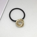 Dettaglio della fibbia in metallo a tre anelli dorati su un elastico per capelli nero - Oro