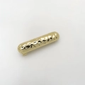 Detail van een gouden gehamerde metalen haarclip met een golvende getextureerde afwerking - Goud