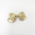 Detailed view of the gold alloy bow hair clip featuring a fine horizontal brushed texture - Gold