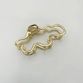 Dettaglio molletta per capelli dorata con linee ondulate irregolari e finitura lucida - Oro