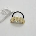 Detail goldener ovaler Metallteile am elastischen Haargummi auf minimalistischem Weiß - Gold