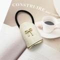 Close-up of beige suede key pouch featuring a golden metal bow and black elastic strap - Beige