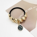 Detail of a black elastic hair tie with a gold twisted metal tube and a grey crystal drop - Twisted Gold