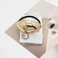 Detail of a U-shaped gold alloy hair tie with a clear crystal water drop charm - Model D Oval Mirror (556-D Gold)