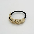 Dettaglio di accessorio in metallo dorato intrecciato su elastico per capelli nero - Stile D Oro