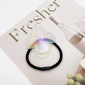 Nahaufnahme eines schillernden Kleeblatt-Anhängers an einem schwarzen Haargummi - 10 (Holografisch Klar)