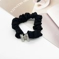 Close-up of black pleated scrunchie with large crystal decoration on a white table - H-Shape Ornament