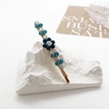 Detail einer blauen Strass-Blumen-Haarklammer auf goldener Legierung mit Glitzersteinen - Blaugrün