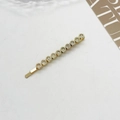 Detailed view of a gold-tone hair clip featuring ten sparkling clear rhinestones set in a row - Clear