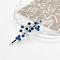 Detail van zilveren haarspeld met blauwe strassteentjes in bloemenrankontwerp op glas - Blauw