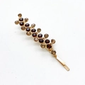 Macro detail of wave-shaped hair clip with brown and amber rhinestones on gold metal base - Brown