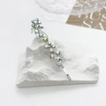 Gros plan d'une barrette argentée à strass colorés sur un support artistique chic - Blanc Iridescent