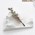 Détail de la barrette dorée élégante avec strass bleus et blancs sur support blanc - Strass Transparents Clip Doré