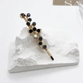 Détail d'une barrette vintage dorée ornée de pierres noires et de cristaux brillants - Gris