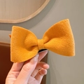 Vibrant yellow wool bow hair clip with textured fabric on a metal duckbill clamp - Orange