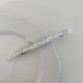 Elegant white marble acetate hair clip with gold logo on a ceramic display dish - Iridescent White