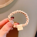 Elastic beige woven hair tie featuring a square decorative bead with a smiley face - Beige