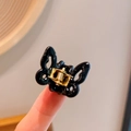 Mini black butterfly hair claw clip with gold spring shown on fingertip for size scale - Black