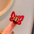 Polished bright red acetate butterfly hair claw clip shown held in fingers for scale - Red