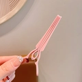 Pink matte hair root clip for volume and bangs styling held by a hand on a warm background - Pink