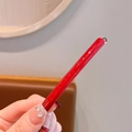 Handmade red acetate hair clip with gold logo detail and glossy finish in hand view - Red
