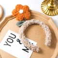 Detail van zachte beige pluche hoofdband met grote oranje bloem op houten achtergrond - Oranje